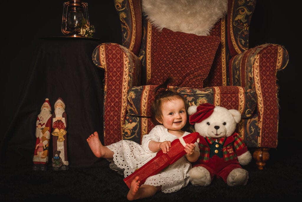 Baby with Christmas decorations and teddy bear.