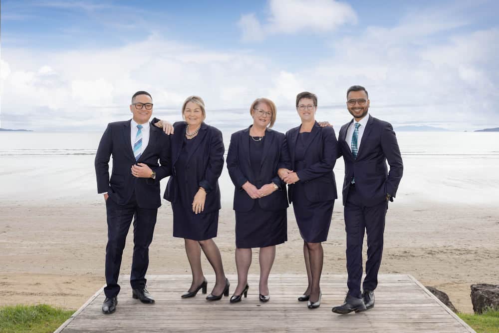 Business professionals posing on beach boardwalk.