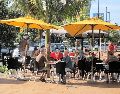 Outdoor cafe with customers under yellow umbrellas.